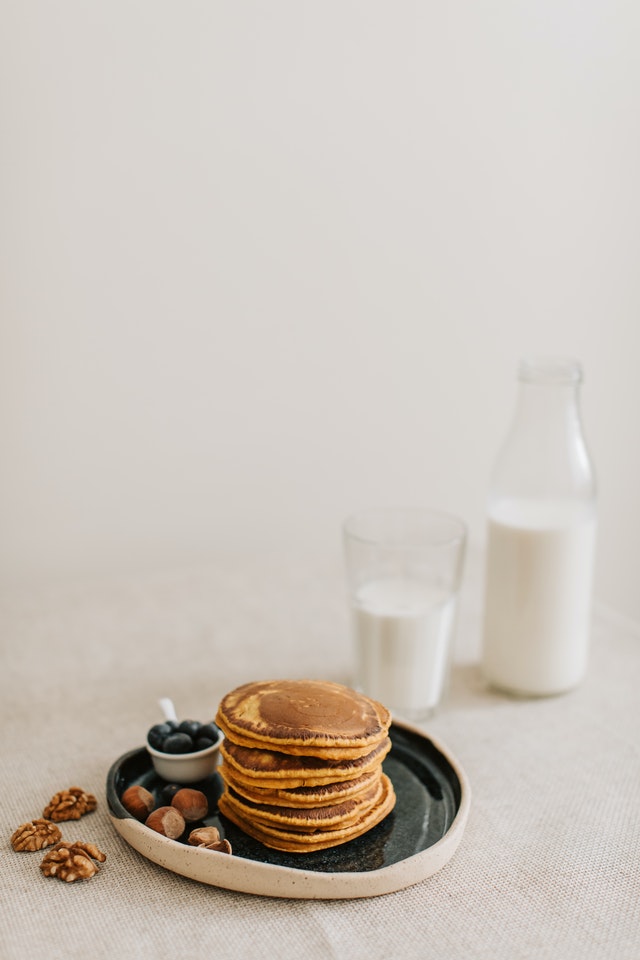 stack of pumpkin spice pancakes on a plate next to a glass of milk